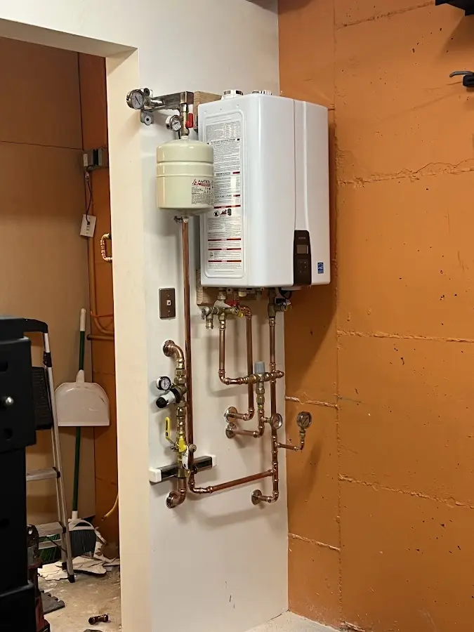 Plumbing technician inspecting water heater connections in Ballwin